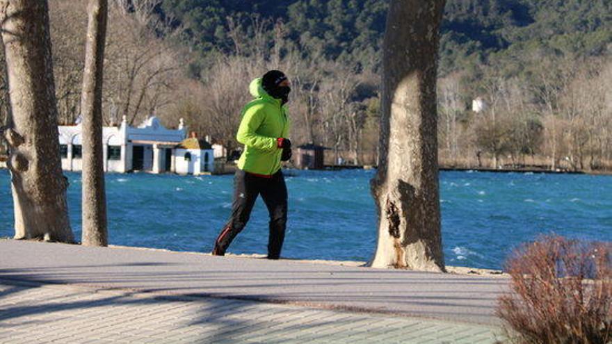 Un home corre a tocar de l&#039;Estany de Banyoles ben abrigat.