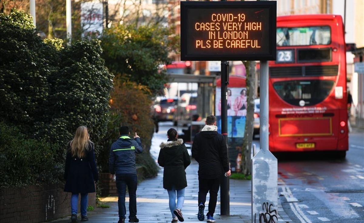 A person gestures towards a sign with a public health information message amid the spread of the coronavirus disease (COVID-19) as new restrictions come into force in London Britain December 20 2020 REUTERS Toby Melville A person gestures towards a sign with a public health information message amid the spread of the coronavirus disease (COVID-19) as new restrictions come into force in London Britain December 20 2020 REUTERS Toby Melville