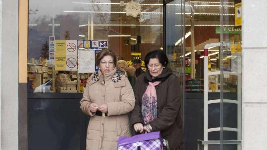 Dos clientas, saliendo ayer por la mañana de hacer la compra en el súper. Tras ellas, un disparo. // Brais L.