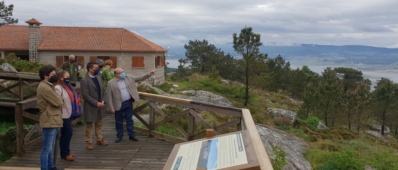 El delegado de la Xunta, acompañado de representantes del PP local, en el mirador de Siradella, con el Aula de la Naturaleza, al fondo.