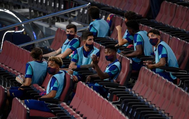 Jugadores del Barcelona con mascarilla en la tribuna antes del partido de fútbol de octavos de final de la Liga de Campeones de la UEFA entre el FC Barcelona y el Nápoles en el estadio Camp Nou de Barcelona.