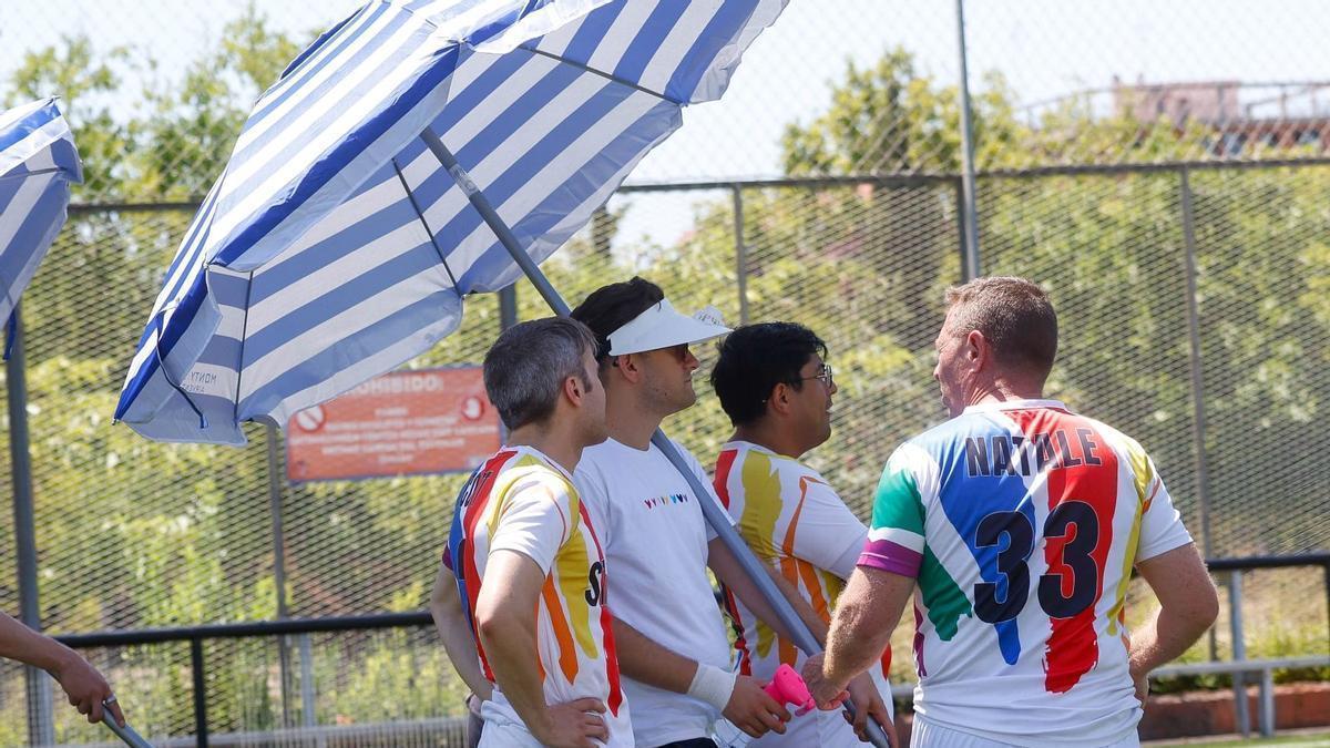 Varios futbolistas se protegen con una sombrilla de la terraza en el campo del Turia