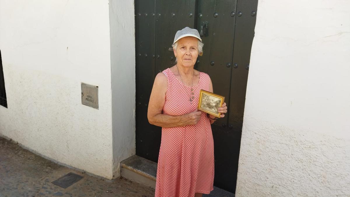 Beatriz, una vecina de Cortelazor, posa con una foto antigua junto a sus hermanas en el que fue un frondoso jardín en su casa.
