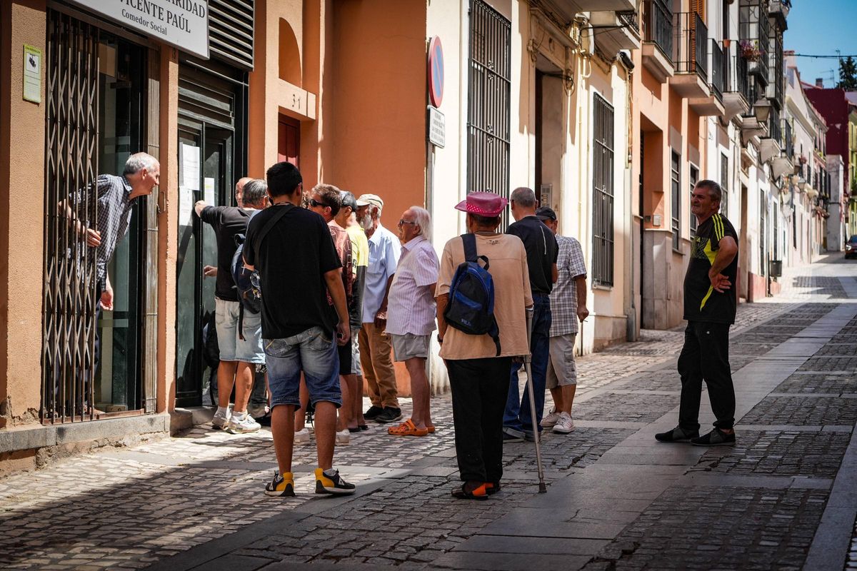 Usuarios del comedor San Vicente de Paúl hacen cola al sol en plena ola de calor.