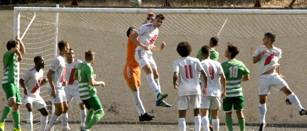 El portero del Huracán, Ismael, salta a por el balón junto a su compañero Fabio.