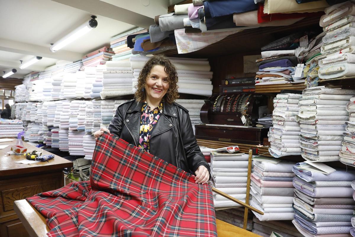 Arantxa Sánchez con una pieza de cuadro escocés en el  mostrador de "Casa Germán", ante la centenaria caja registradora.