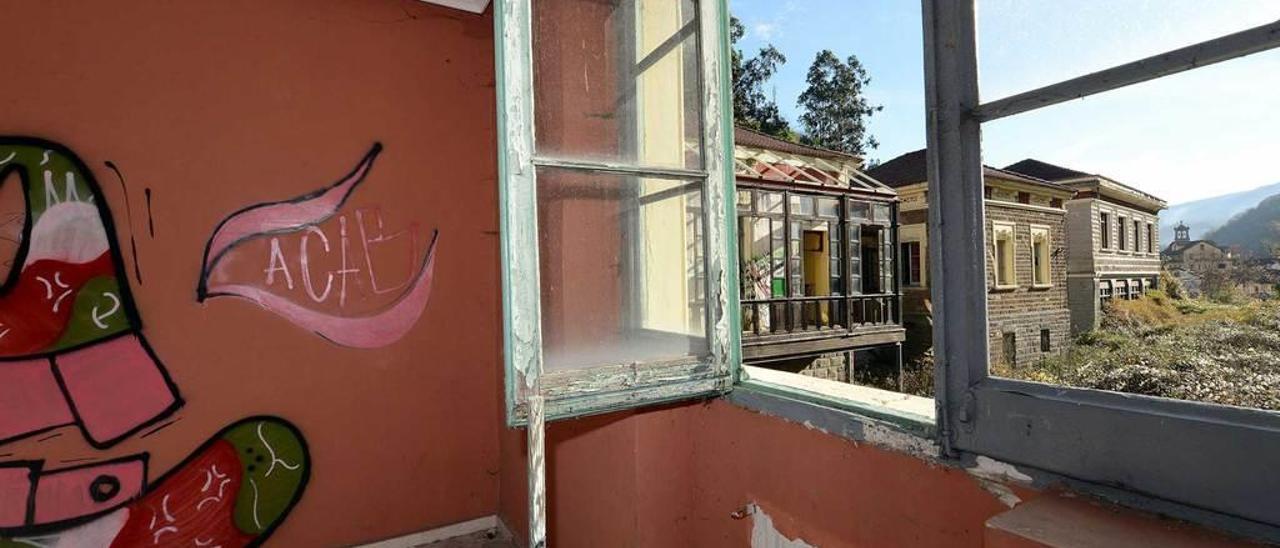 Arriba, una de las salas del edificio, totalmente destrozada. Debajo, una pintada en la pared de una habitación con la ventana rota.