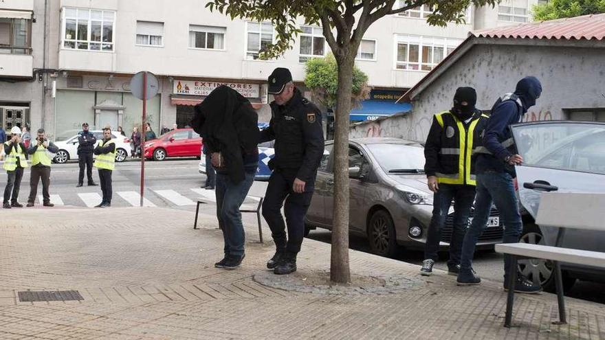 Agentes de la Policía acceden con uno de los detenidos al edificio del piso investigado. // Brais Lorenzo