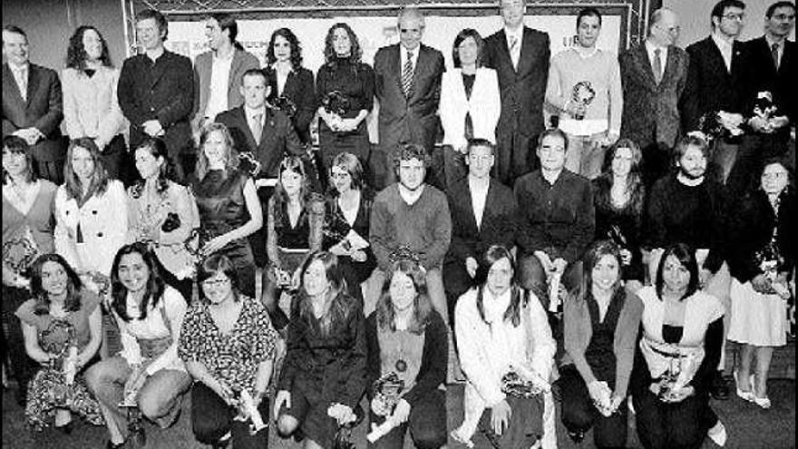 Foto de familia del presidente de la Xunta, la conselleira de Educación y representantes de las universidades, con los licenciados premiados. / j. lores