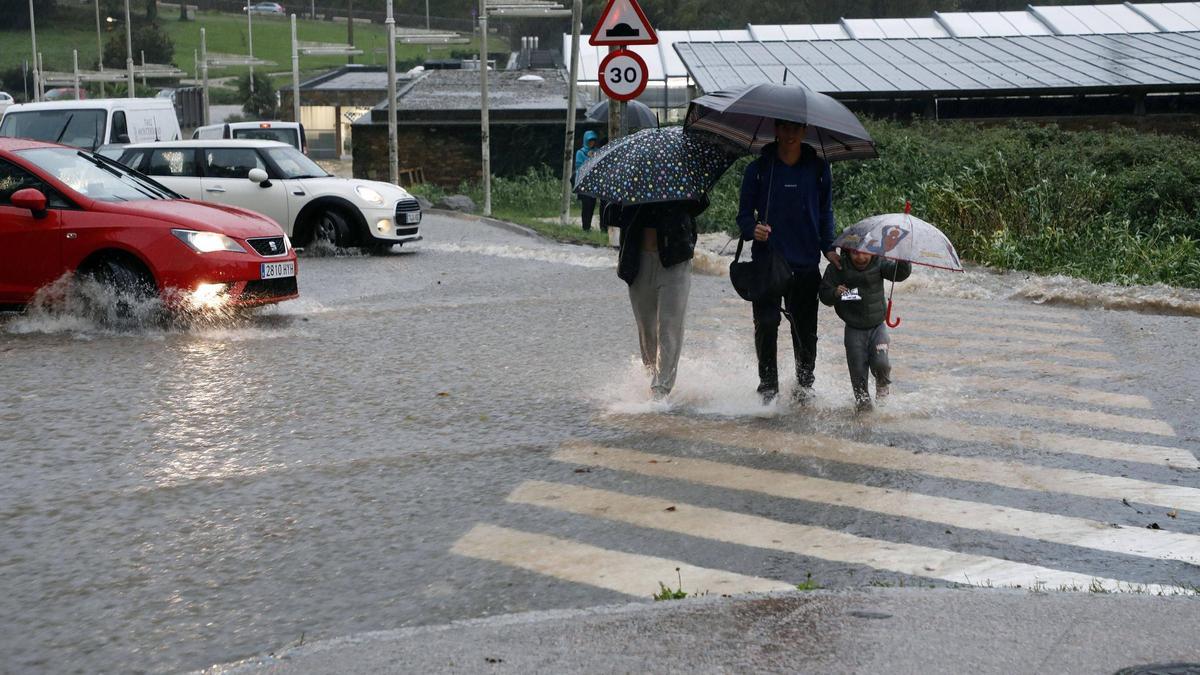 Personas cruzando un paso de peatones en Sar en un día de temporal