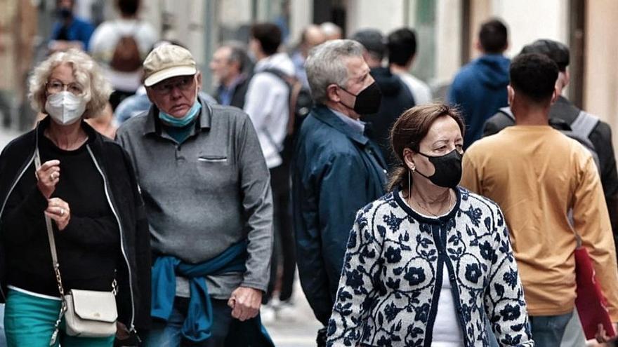 Varias personas pasean con y sin mascarilla por la calle