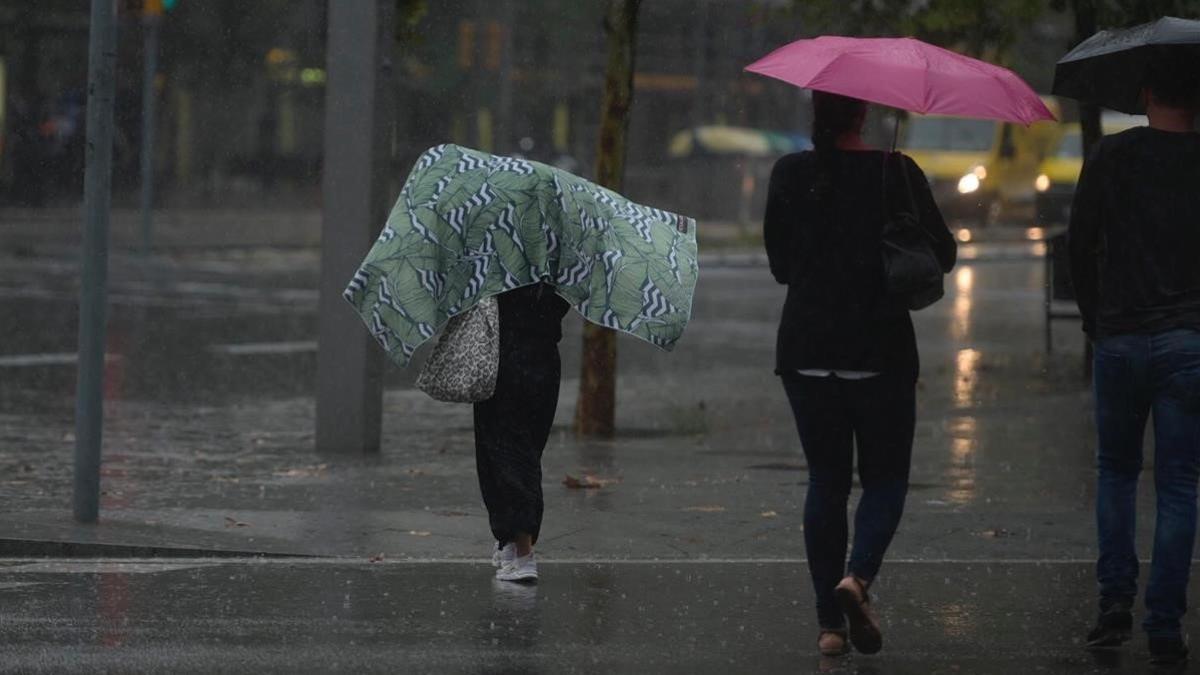 Paseantes bajo la lluvia en Barcelona, este martes.