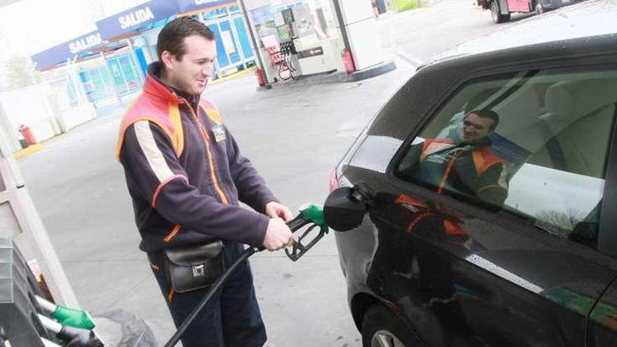 Un operario de una gasolinera surte combustible a un vehículo.