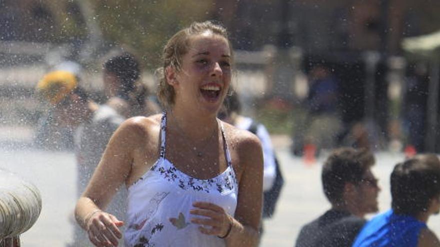 Una joven se refresca en una fuente.