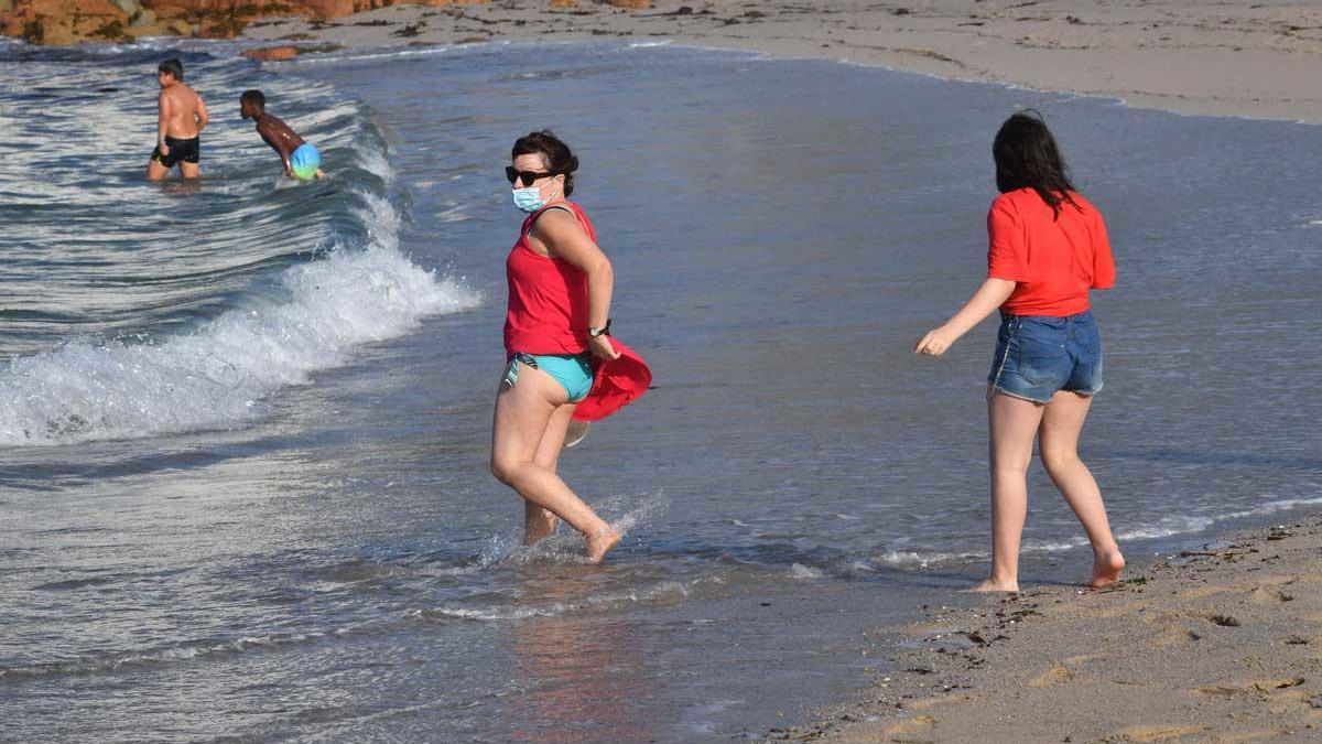 Bañistas con masacarilla en la playa.