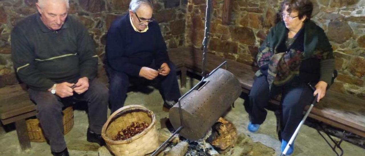 Germán Castaño, Manuel de la Fuente y Carmen Fernández preparan las castañas para asar.