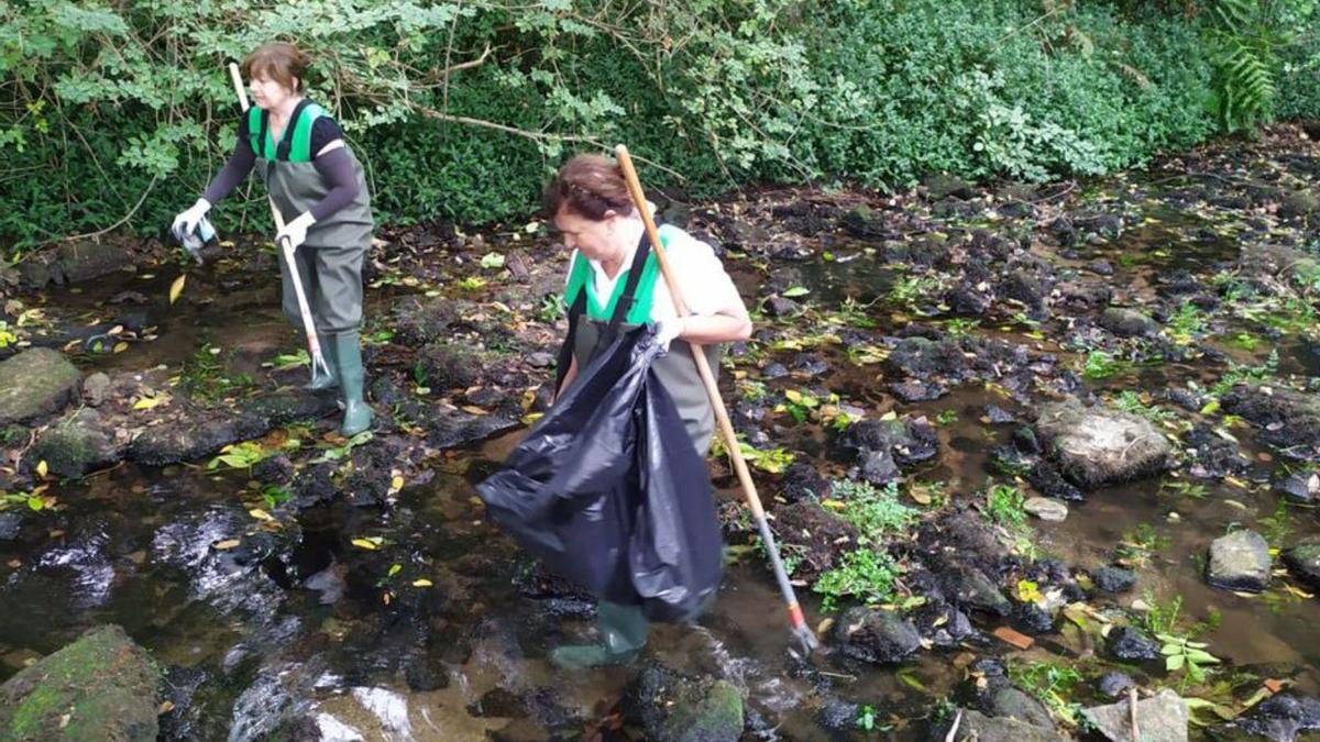 Dos mujeres colaboran en la limpieza del río Gafos.   | // FDV