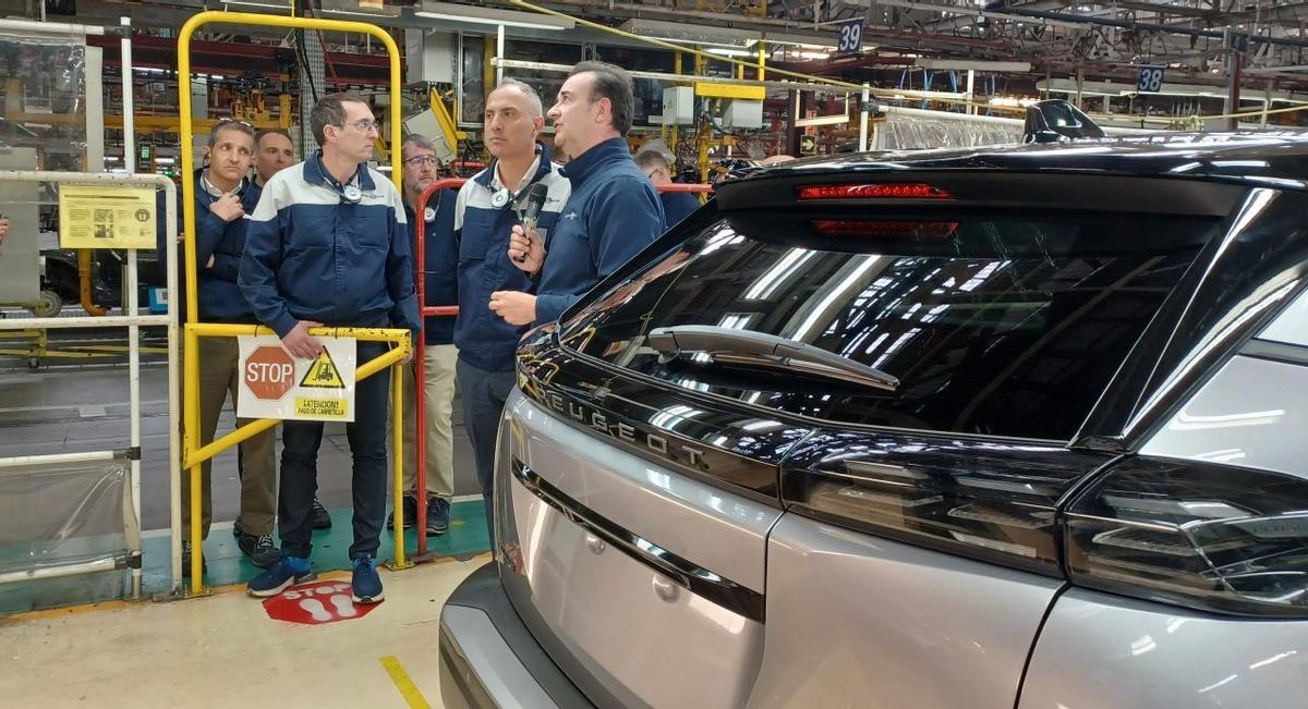 Cianacia escuchando atentamente una explicación junto a un Peugeot 2008