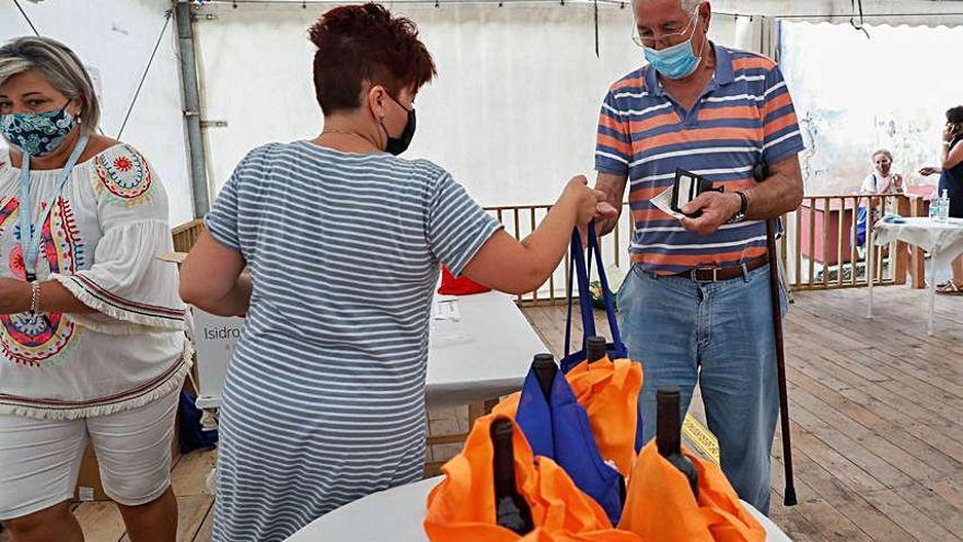 Los vecinos, ayer, recogiendo el bollo y el vino en la carpa de la asociación.