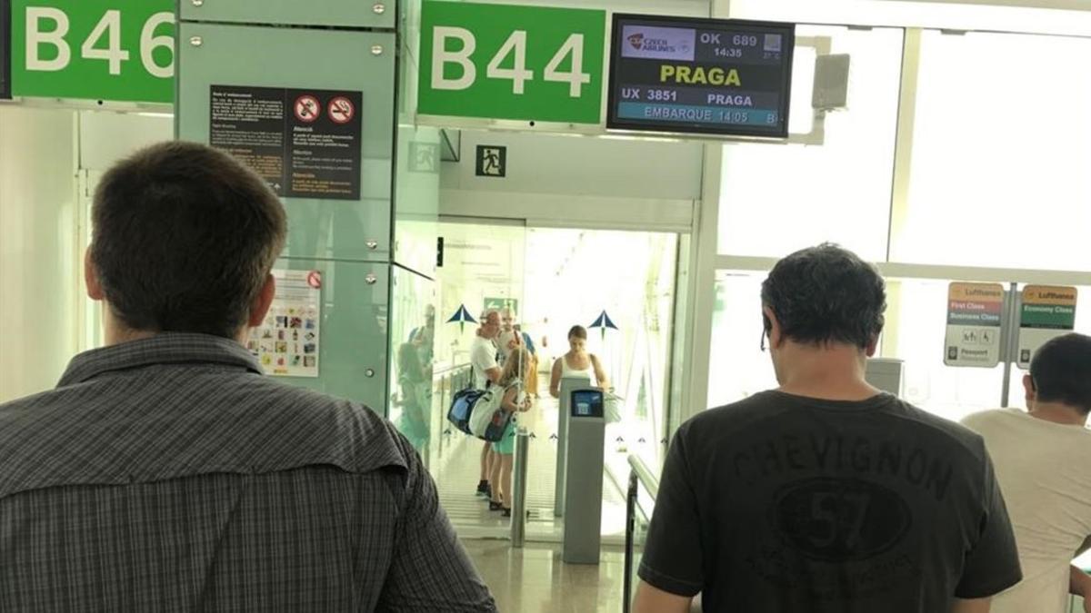 Pasajeros que esperan embarcar en el vuelo OK-689 de Czech Airlines observan como los que llegan no pueden acceder al hall de El Prat, pues no hay nadie que les abra la puerta.