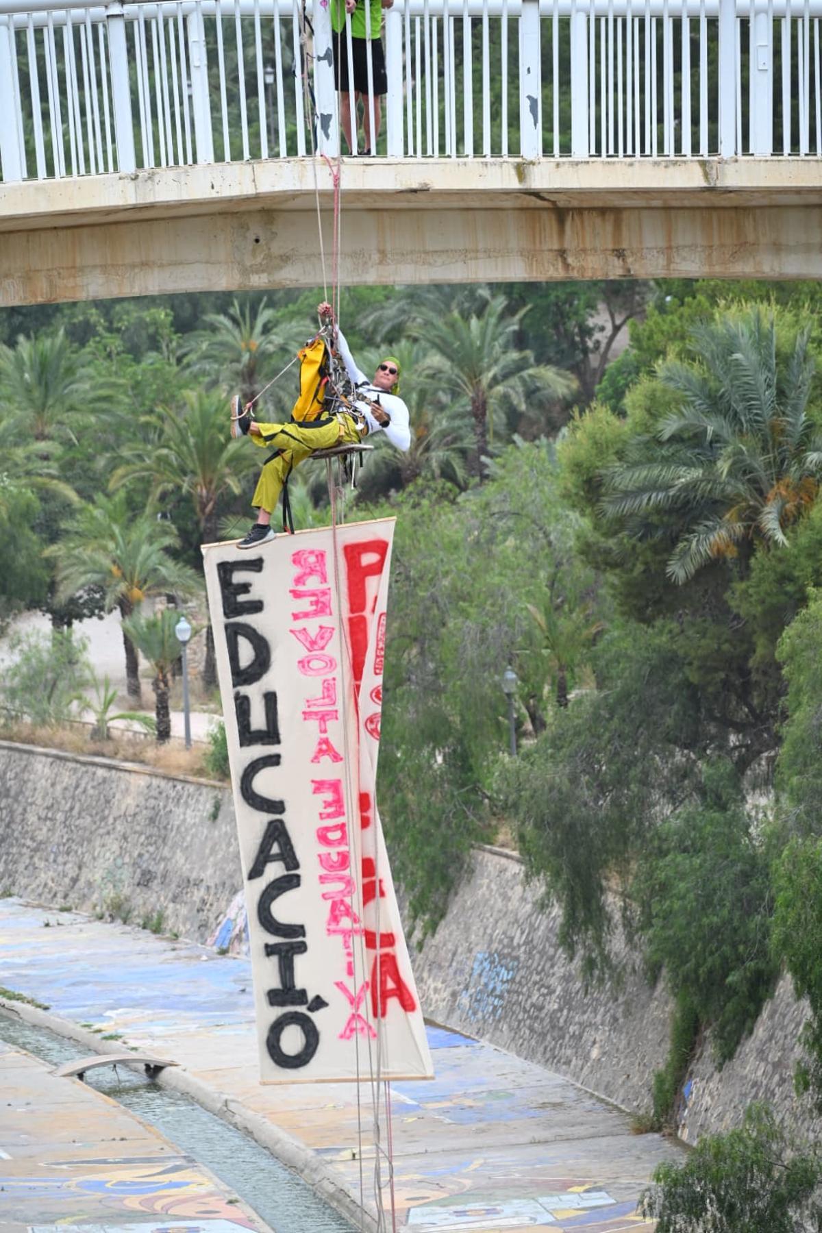La huelga educativa escala en Elche: un profesor se cuelga de un puente con una pancarta