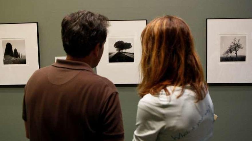 Dos visitantes observan una de las fotografías de Michael Kenna en el Evaristo Valle.