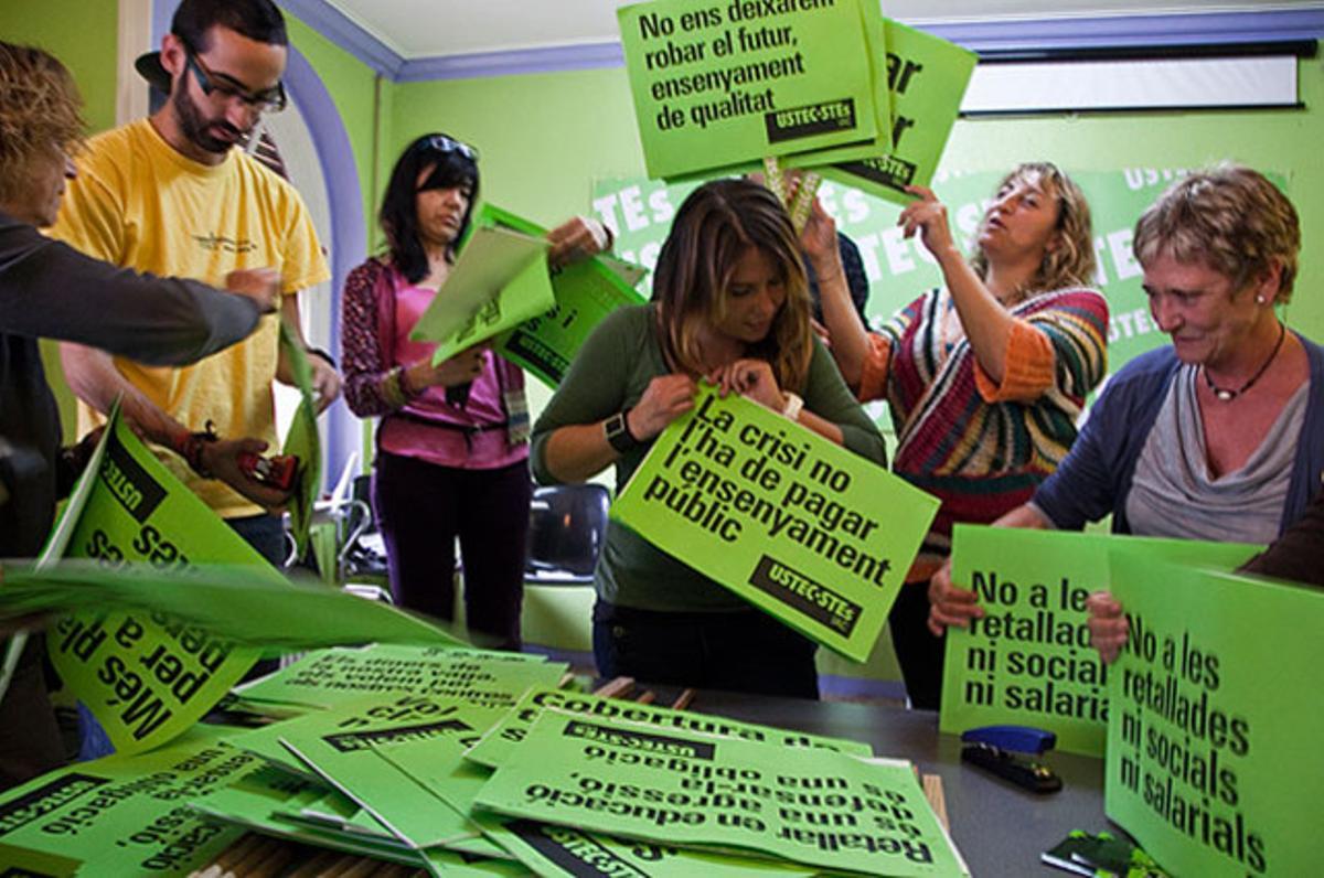 Afiliats i col·laboradors del sindicat USTEC treballen en l’elaboració de cartells per a la vaga d’ensenyament del 22-M, a la seu del sindicat de Barcelona.