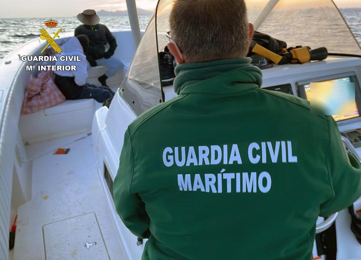 Un agente del Servicio Marítimo en la lancha de Altea con dos de los tripulantes detenidos.