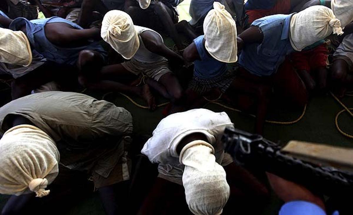 Una persona armada vigila un grup de presumptes pirates somalis a Mumbai (Índia). L’armada índia va capturar diumenge 28 presumptes pirates somalis d’un vaixell pesquer de Tailàndia, després d’un breu intercanvi de trets a l’Oceà Índic.