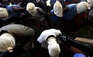 Una persona armada vigila un grup de presumptes pirates somalis a Mumbai (Índia). L’armada índia va capturar diumenge 28 presumptes pirates somalis d’un vaixell pesquer de Tailàndia, després d’un breu intercanvi de trets a l’Oceà Índic.