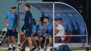 Lionel Scaloni, de pie en primer término, mira el entrenamiento de sus pupilos con Sergio Kun Agüero, ya retirado, sentado en el banquillo y vestido para jugar.