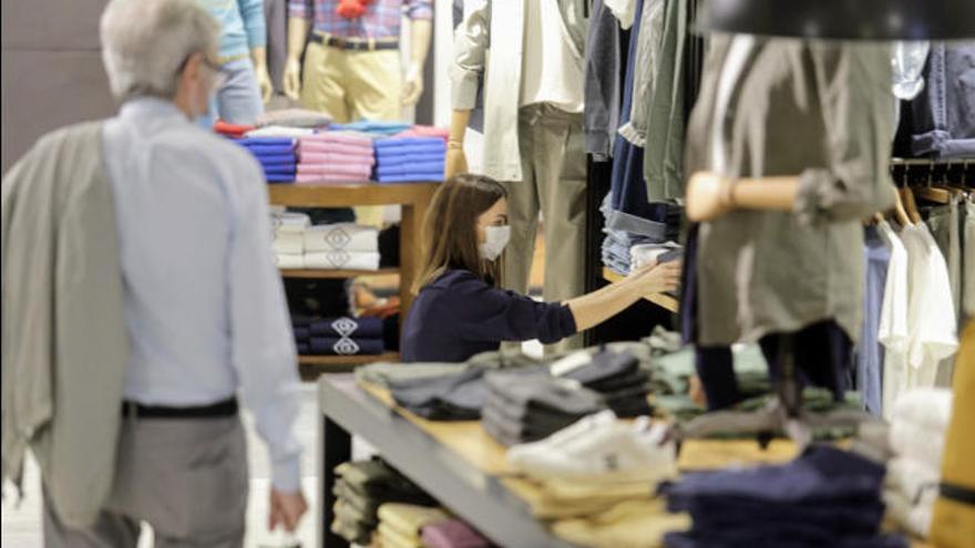 Una empleada de una cadena nacional ubicada en la capital tinerfeña coloca unas prendas en una repisa.