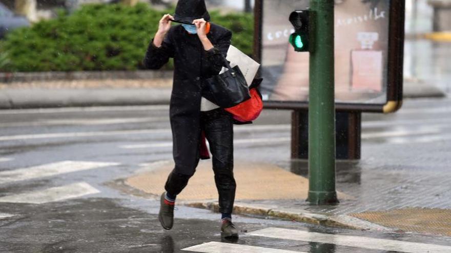 Una mujer se resguarda del viento, el frío y la lluvia, este miércoles por A Coruña. |   // VÍCTOR ECHAVE