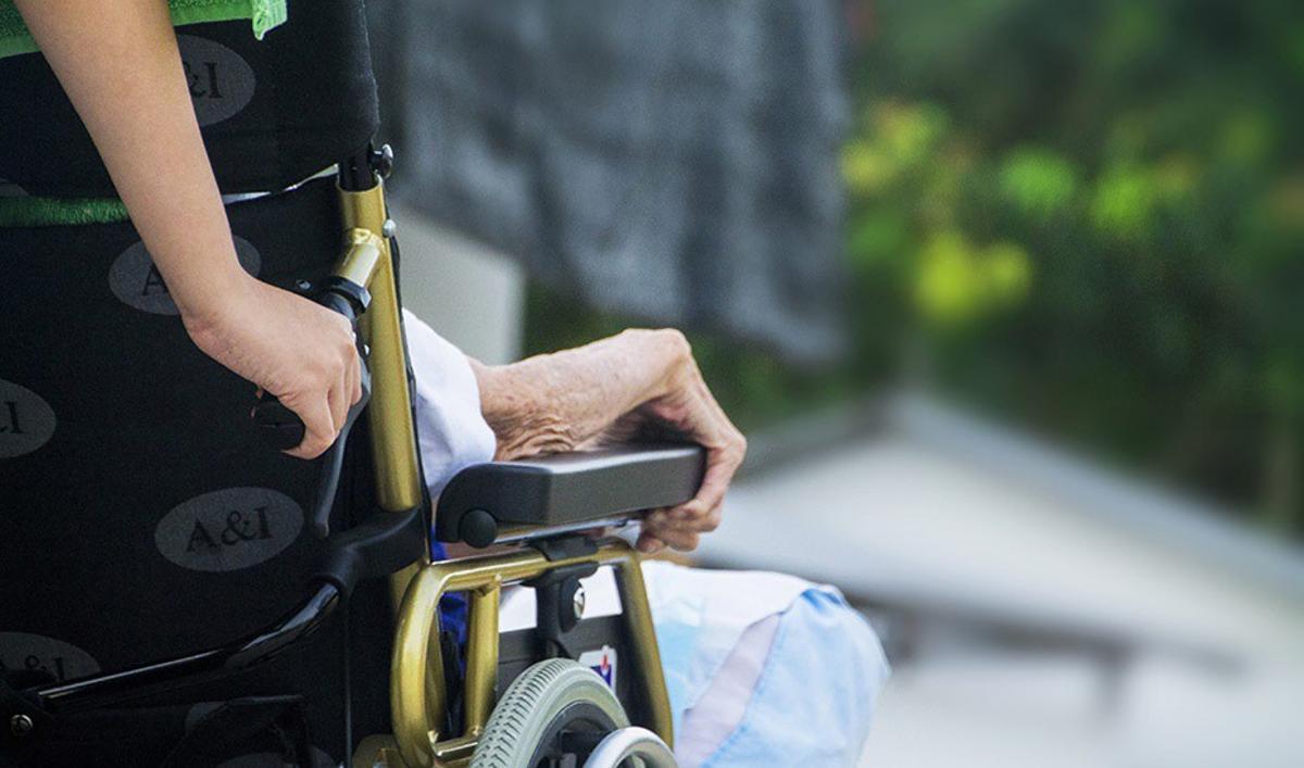 Una cuidadora ayuda a una mujer impedida.