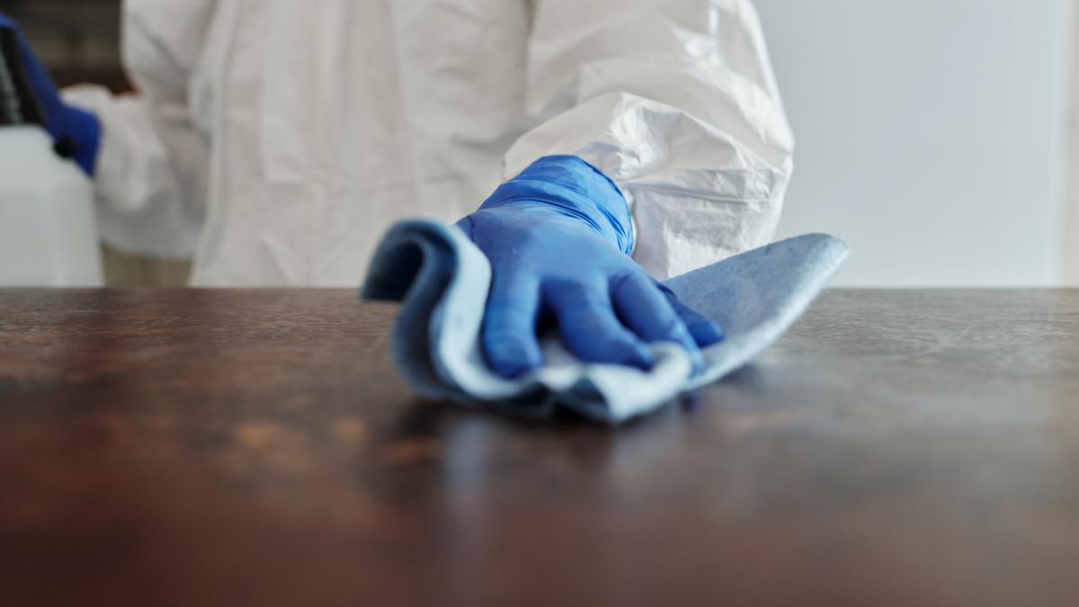 Una persona desinfecta la superficie de una mesa contra el coronavirus.