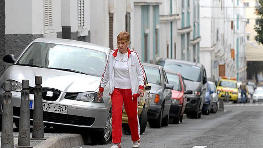 Una señora tiene que caminar por el asfalto porque la acera está tomada por los coches en Schamann. iSANTI BLANCO