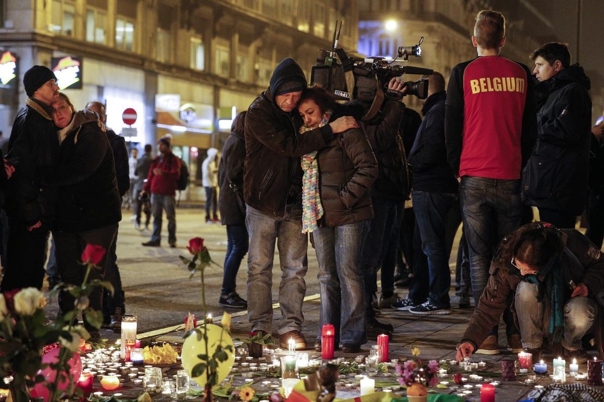 Un grupo de personas rinde homenaje a las víctimas de los atentados en la Place de la Bourse, de Bruselas.