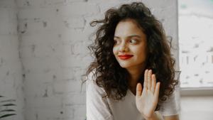 Una mujer saluda con la mano. 