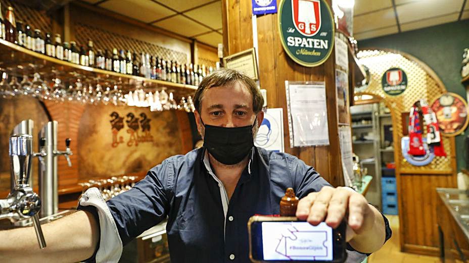 Manrique Saras, con un teléfono que muestra el programa municipal en su cervecería. |  MARCOS LEÓN