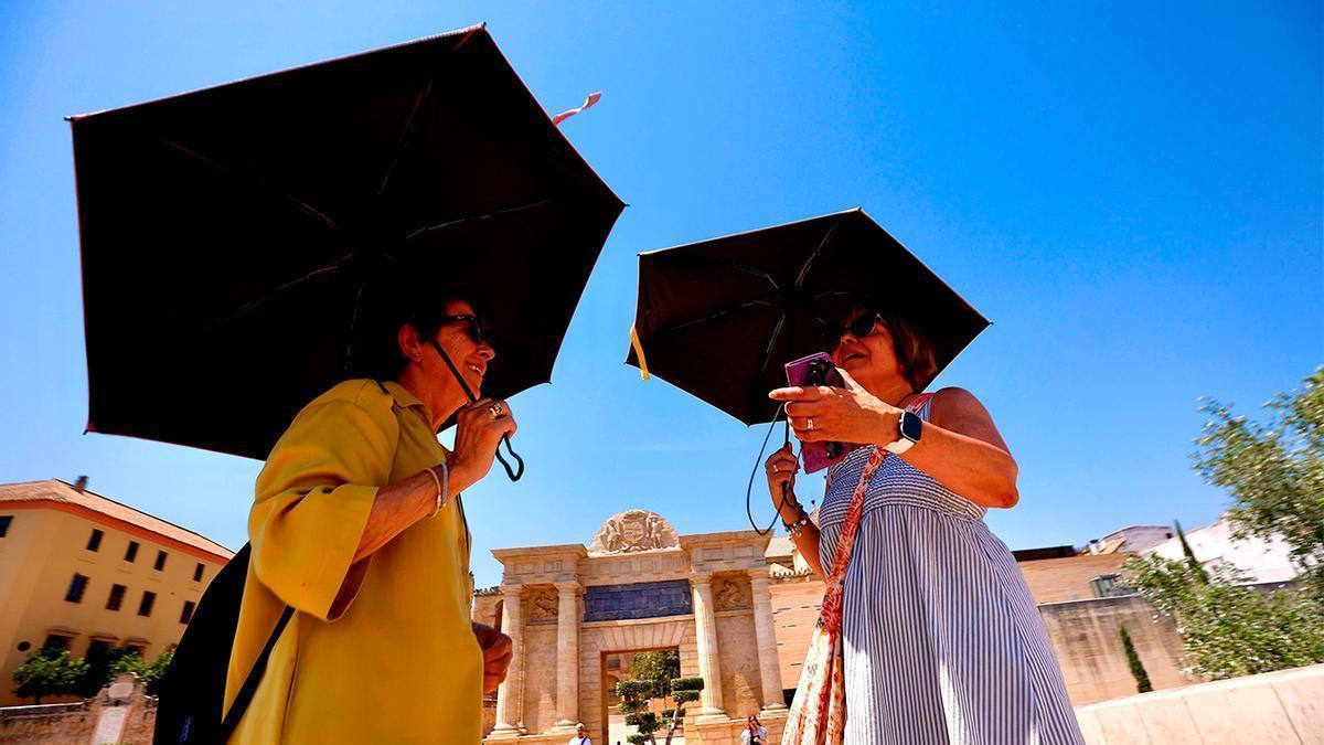 Dos mujeres se protegen del calor con paraguas.