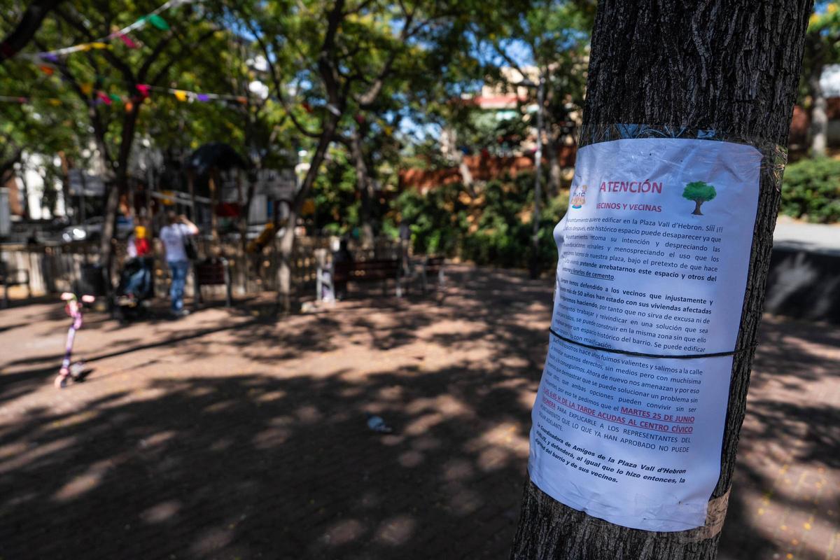 Zona de juegos en la plaza de la Vall d'Hebron, en Barcelona, con un cartel en primer plano en contra de que se edifique en parte del parque.
