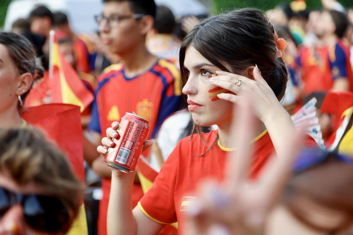 Una joven siguiendo el partido de este domingo mientras toma un refresco en las calles de Murcia.