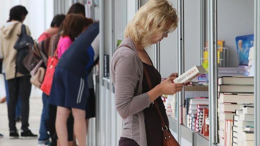 Una mujer mira un volumen en la Feria del Libro