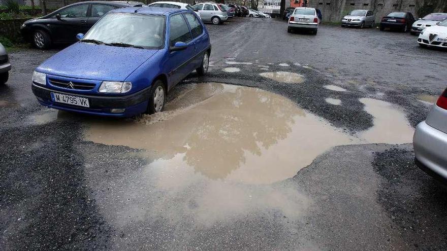 Un vehículo, ayer, sorteando el charco existente en el acceso al parking. // Bernabé/Cris M.V.