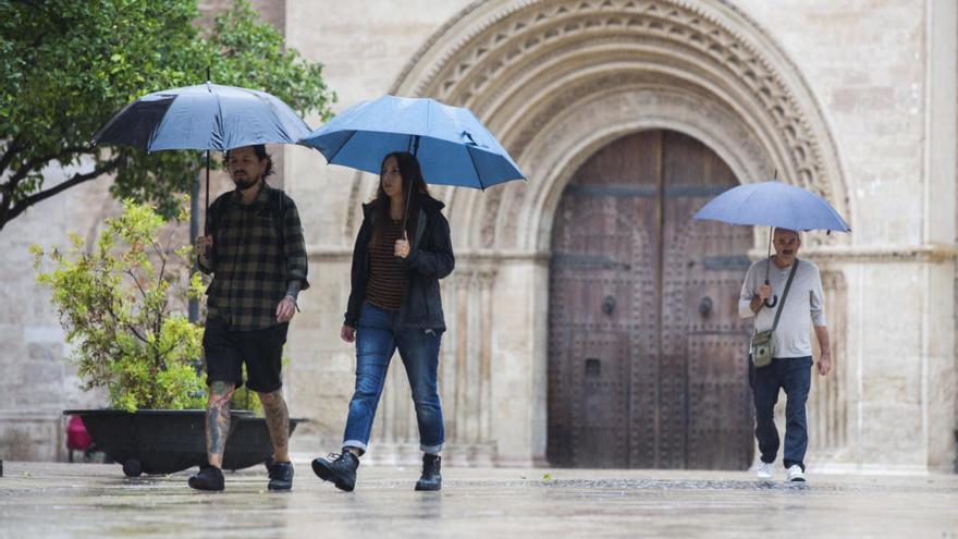 Varias personas se protegen de la lluvia en el centro de València