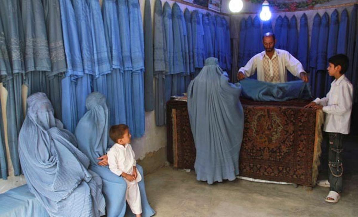 Un home ven burques a un grup de dones aquest dilluns en una botiga d’Herat, a l’Afganistan. Malgrat els progressos dels últims anys, l’economia afganesa fins i tot depèn en bona mesura de l’ajuda externa. Gran part de la població no té vivenda, aigua potable, electricitat, atenció mèdica i feina.