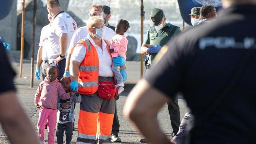 La voluntaria de Cruz Roja María Afonso sujeta en el puerto de Arguineguín (Gran Canaria) a tres niños rescatados por Salvamento Marítimo el 20 de mayo de 2020 de una patera, tras proporcionarles algo de comida y ropa seca.