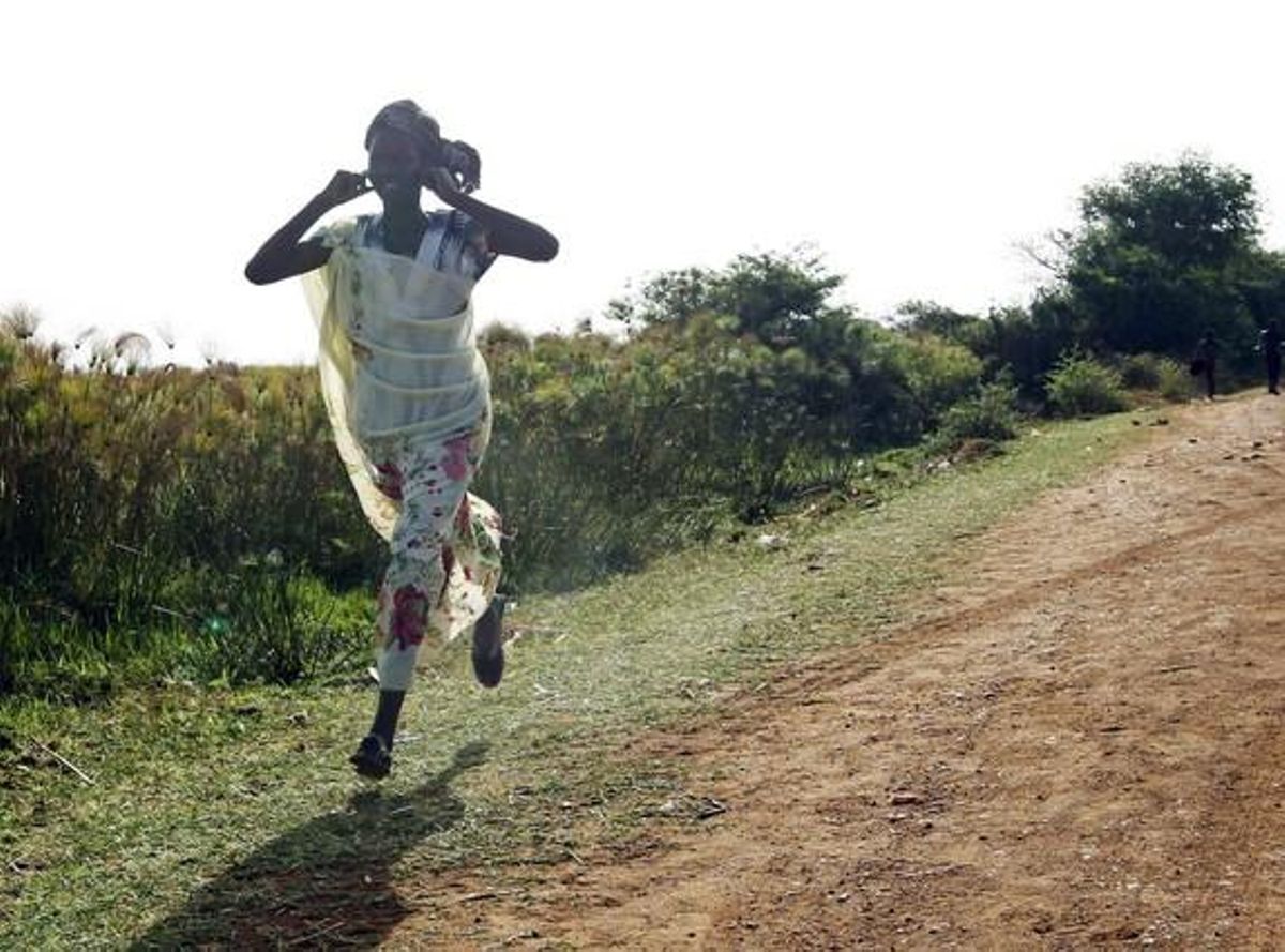 Una mujer corre por una carretera durante un ataque de la fuerza aérea de Sudán en Rubkona, cerca de Bentiu.