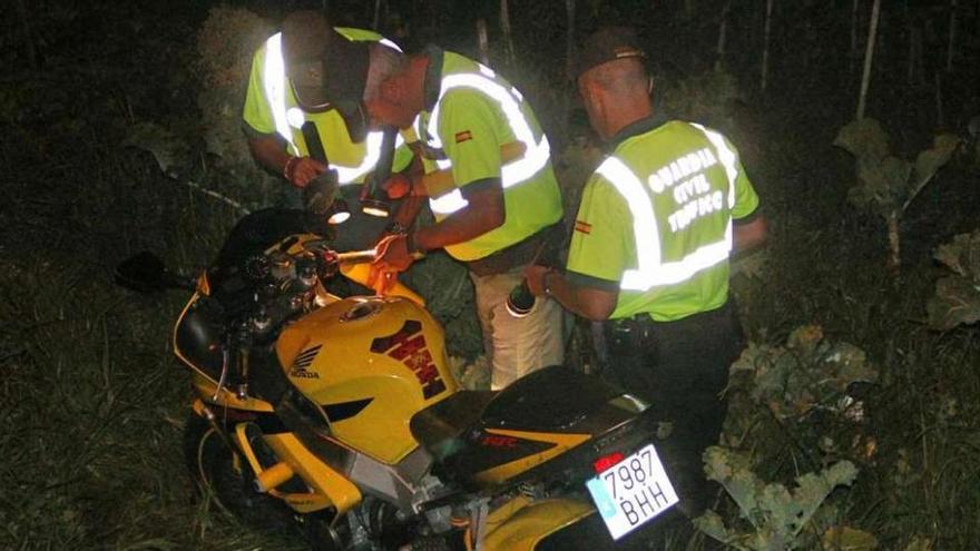 Agentes de la Guardia Civil de Tráfico recogen la moto siniestrada en una finca de Cela.