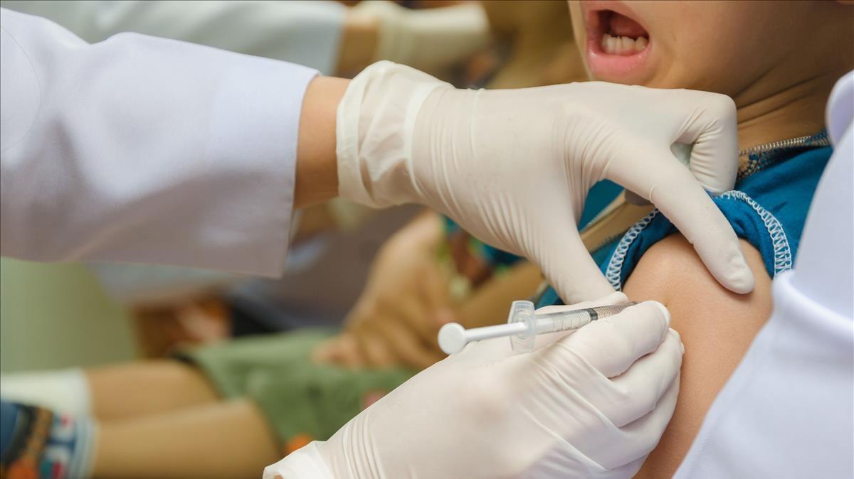 Un pediatra pone una vacuna a un niño.
